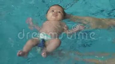一只手上的婴儿在游泳池里游泳